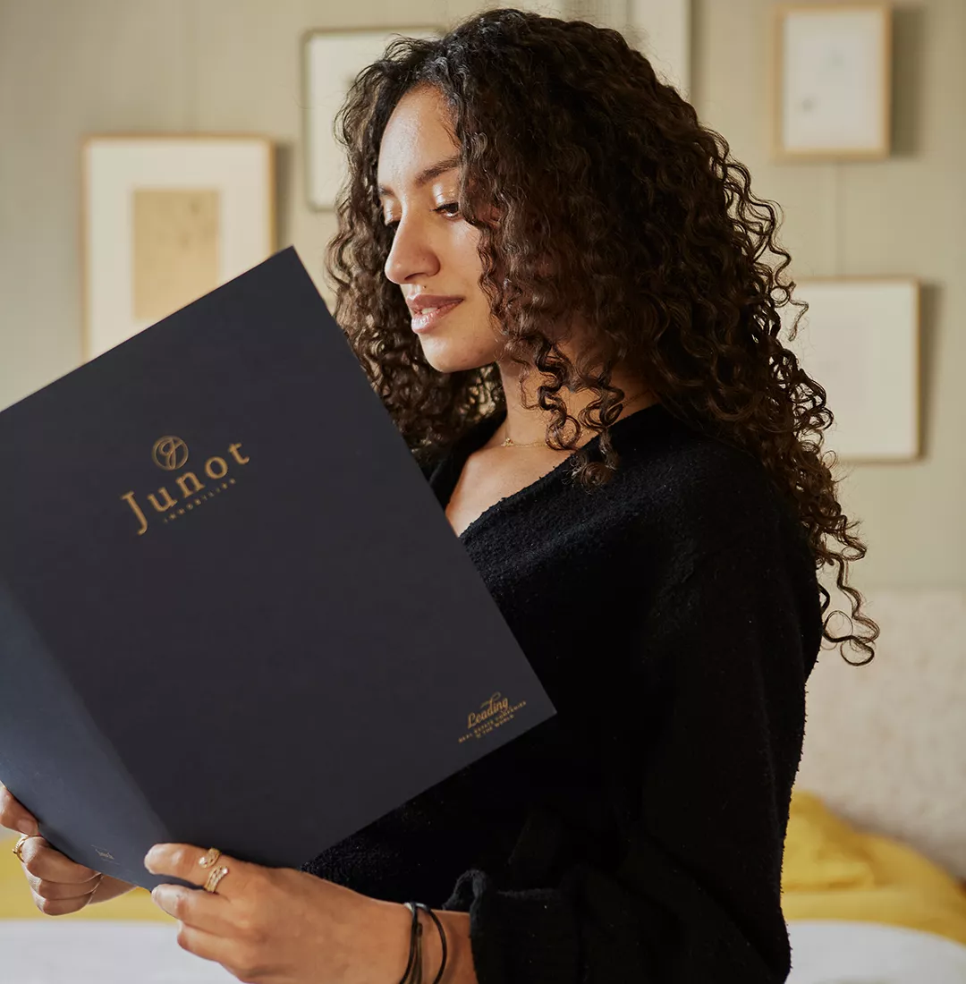 A client of a relocation company consults the Junot brochure for the rental of a luxury property with Junot Rental & Management