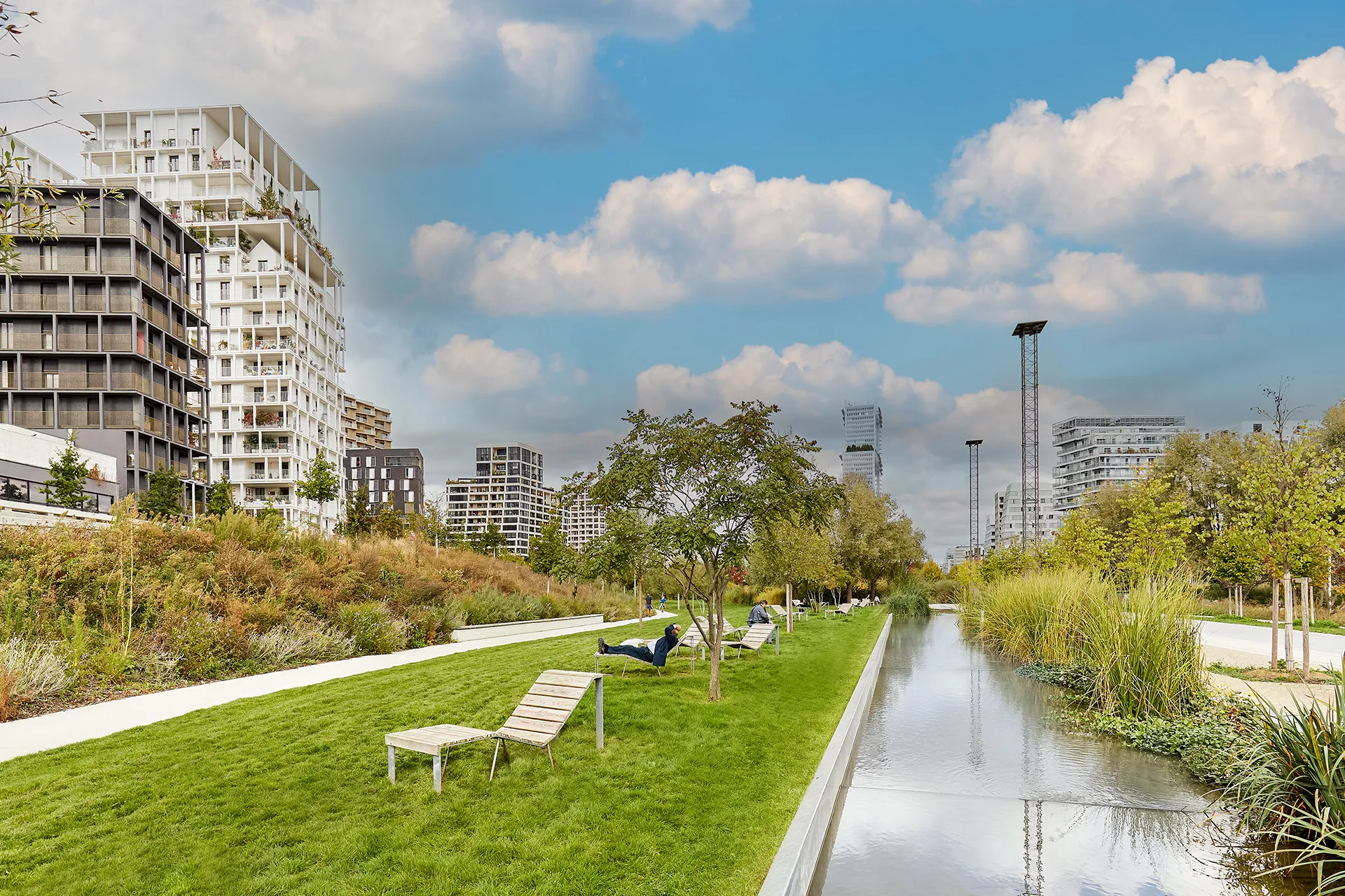 Parc Martin Luther King dans le quartier des Batignolles, avec chaises longues, arbres verdoyants et immeubles modernes en arrière-plan.
