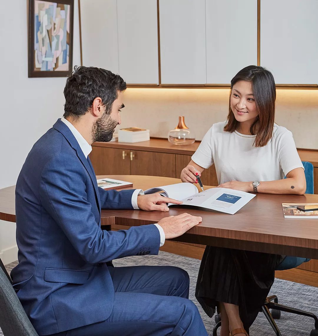 Deux agents immobiliers devant une brochure Junot pour vendre un appartement de luxe