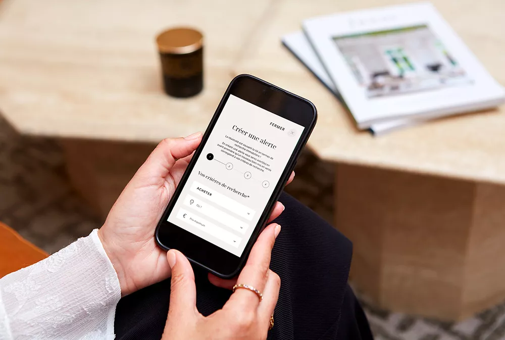 Woman with a mobile phone creating an email alert on the Junot website