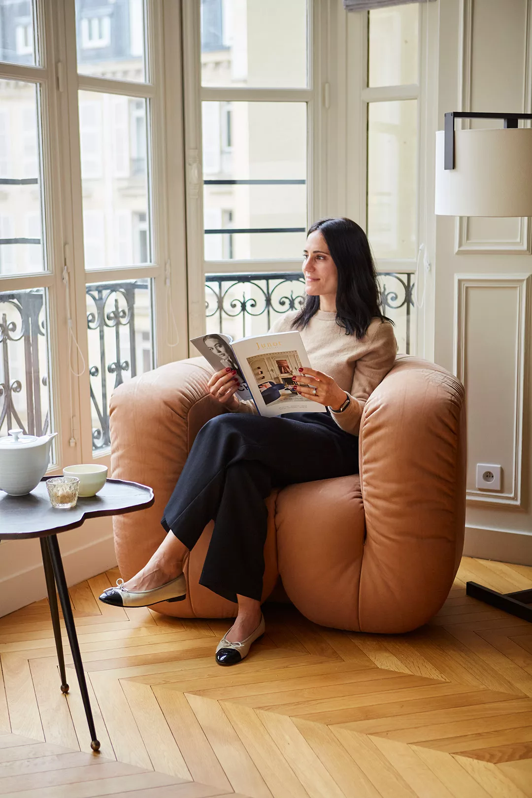 A Junot client reading while sitting in a designer armchair in an apartment sold in Paris by Junot