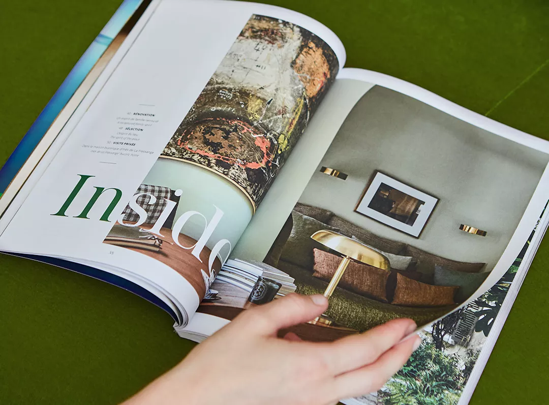 A person leafing through the Junot Magazine against a green background